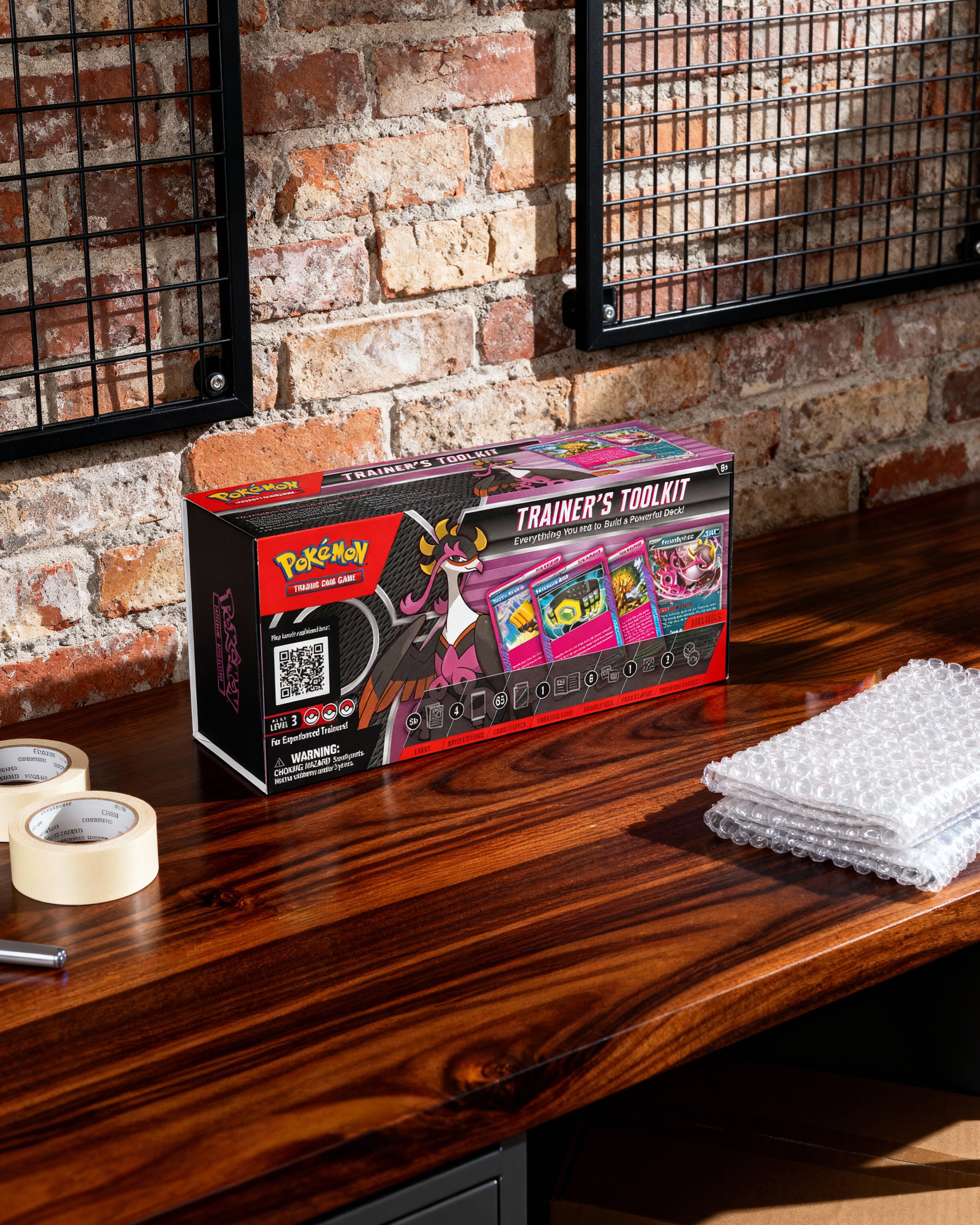 Pokemon Trainer's Toolkit box on a wooden surface with a brick wall background