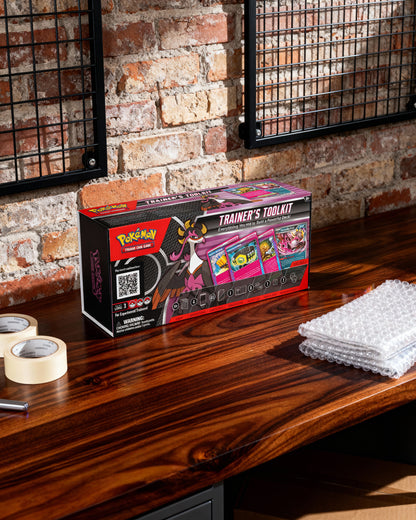 Pokemon Trainer's Toolkit box on a wooden surface with a brick wall background