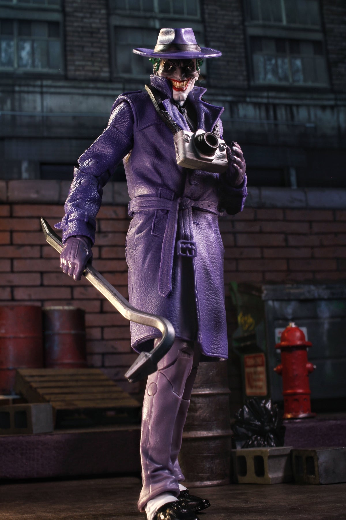 Joker The Comedian DC Multiverse 7-Inch Figure — Three-Quarter View Holding Crowbar Against Brick Wall