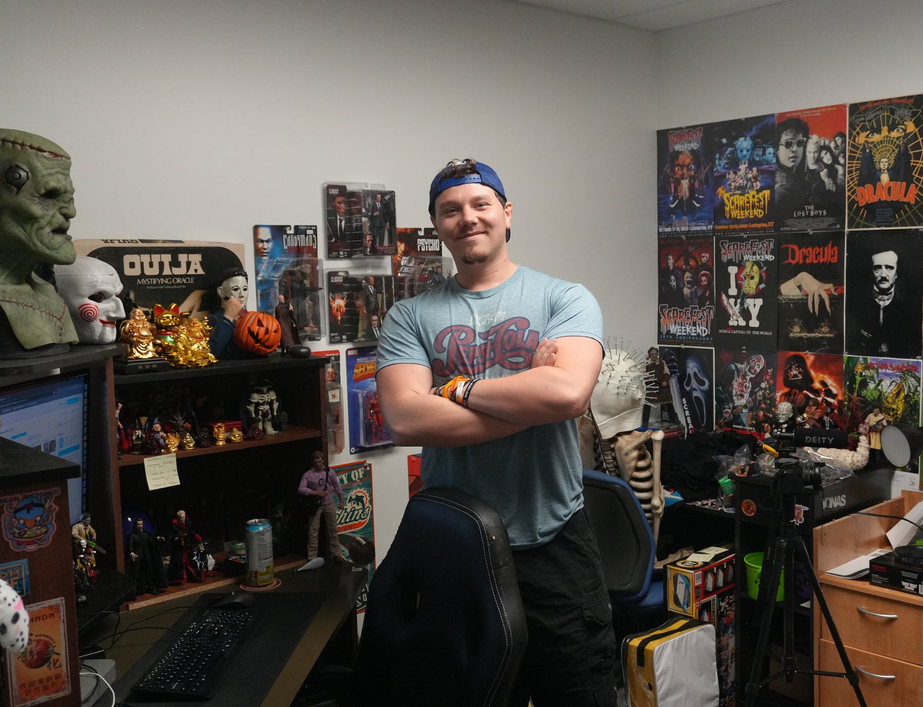 Devin, Social Media Manager at Jay’s Toys & Games, arms crossed in front of a wall of horror posters