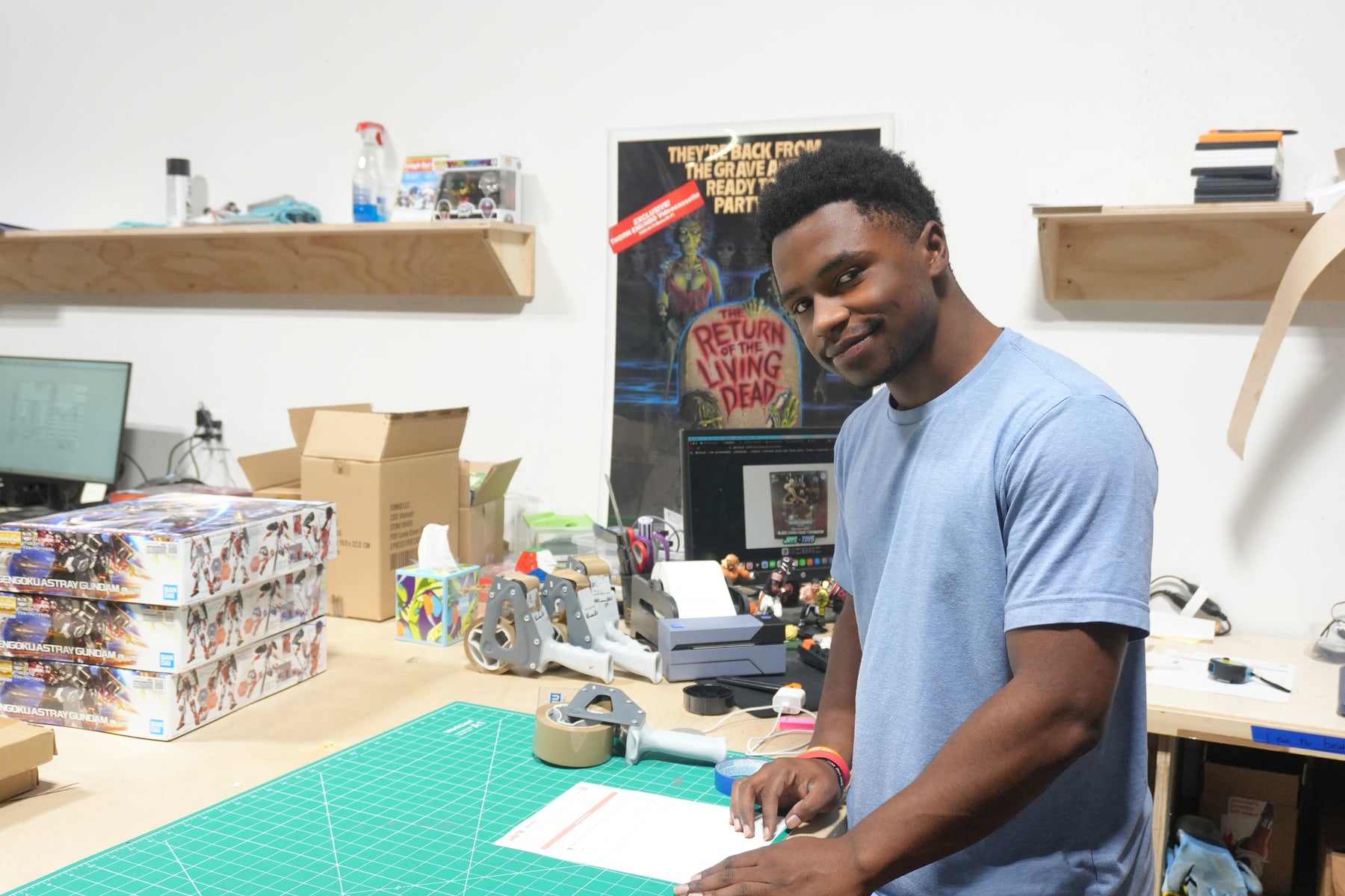 Tashawn, Fulfillment Specialist at Jay’s Toys & Games, at the packing bench with a stack of Gundam kits